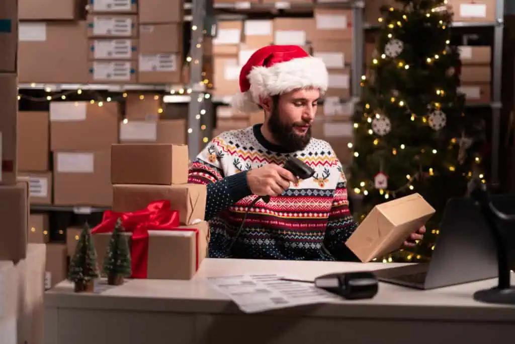 Santa scanning barcode on delivery parcel. Worker scan barcode of cardboard packages before delivery at storage working on Christmas. Male manager factory warehouse scanning labels