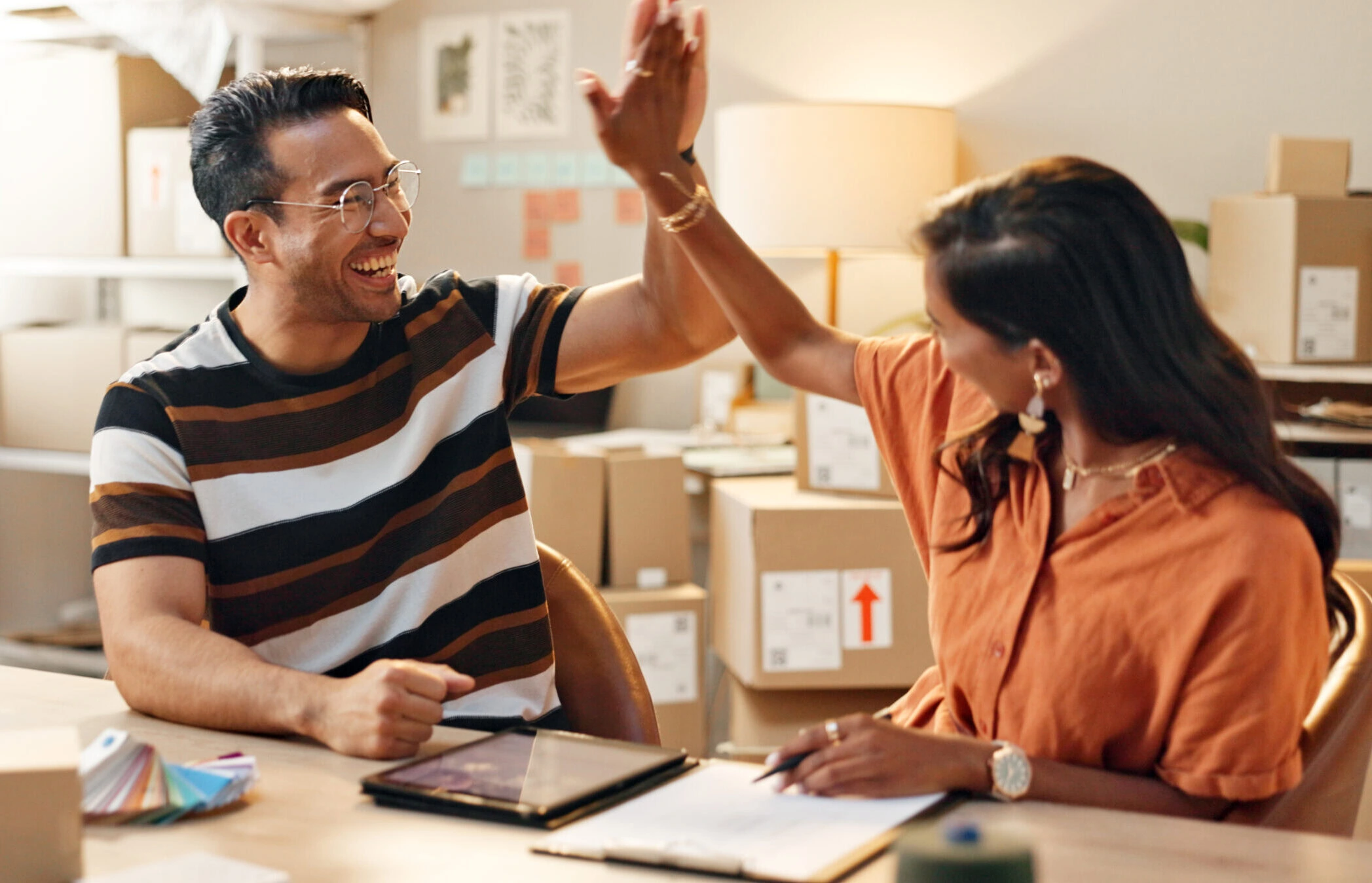 Small business, high five or teamwork for design, success or sale target with color swatches at store. Excited man, goals or happy woman on tablet for online promotion, collaboration or winning deal