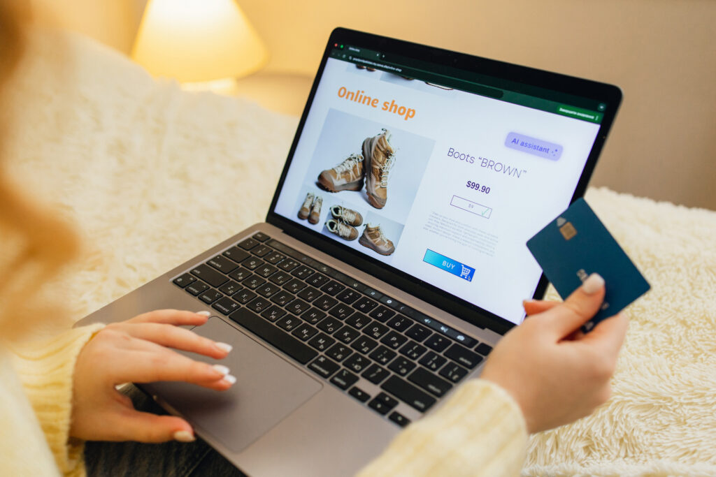 Person Shopping Online with AI Assistance On Laptop While Holding Credit Card In A Cozy Home Setting